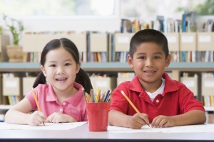 Kindergarten children sitting at desk and writing in classroom